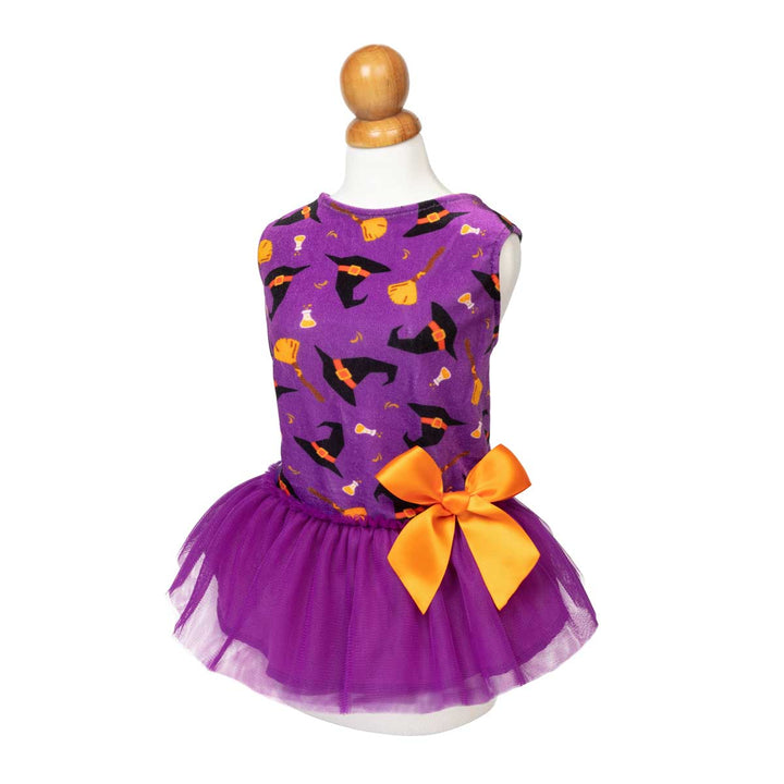 Halloween dog tutu dress displayed on a white mannequin torso. Featuring a pattern of black witch hats, orange pumpkins, and broomsticks on a purple background
