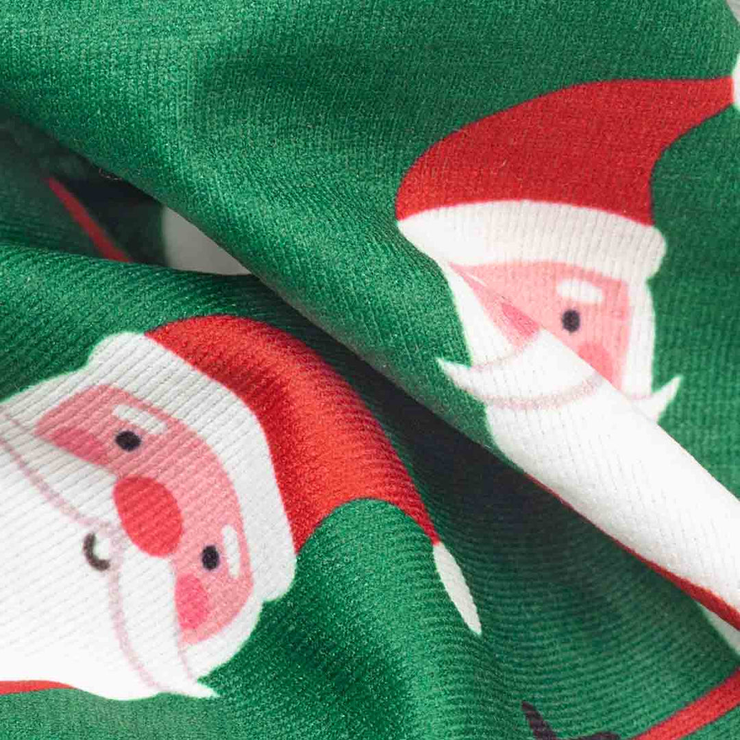 close-up of green fabric printed with a repeating Santa Claus face pattern, showing red hats, white beards, and small black eyes and noses