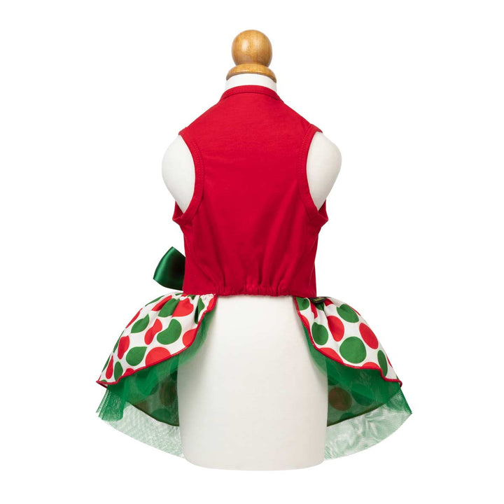 Red dog Christmas dress from the back on a white mannequin, featuring a green bow and a flared back skirt with a red and green polka dot pattern and green tulle