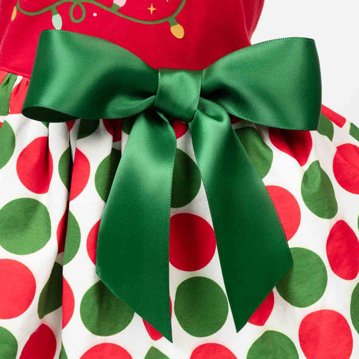 Close-up of a Christmas-themed dog tutu featuring a large green satin bow at the waist, a red top with holiday lights, and a white skirt with red and green polka dots