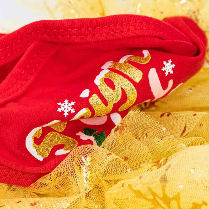 Close-up of red and gold fabric with glitter lettering and mesh from a Christmas dog dress.
