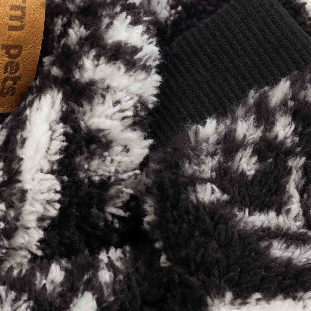 Close-up detail of fluffy black and white dog pajamas featuring soft fleece texture and ribbed cuffs.