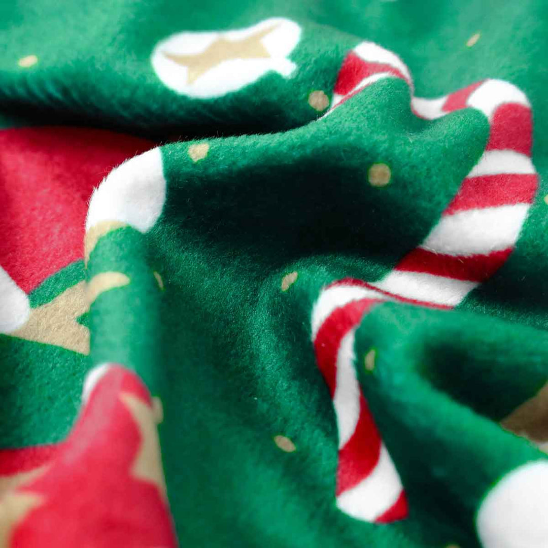 Close up of green dog pajamas with candy cane and Santa hat print.