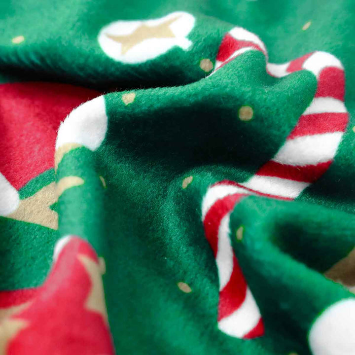 Close up of green dog pajamas with candy cane and Santa hat print.