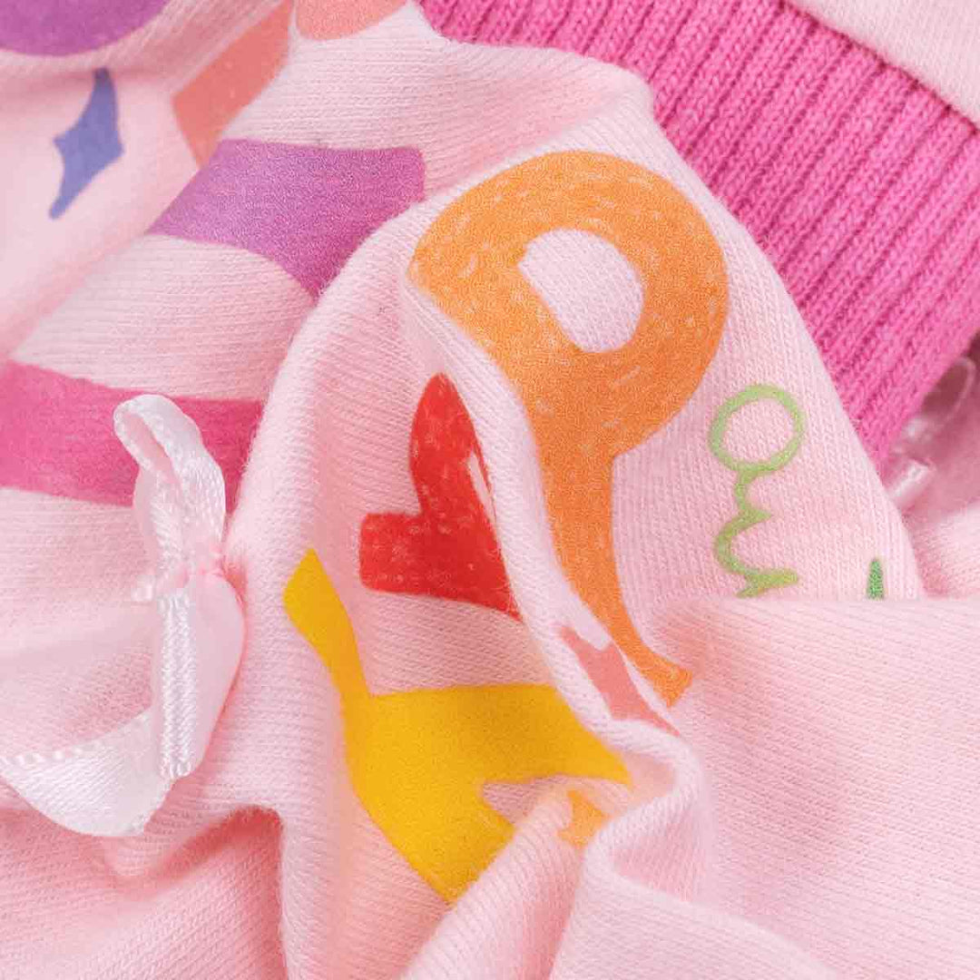 Close-up of pink birthday dog pajamas fabric with colorful print and soft cotton blend texture.