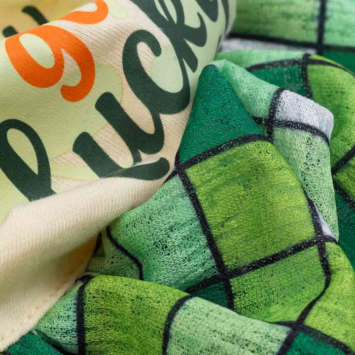 Close-up of green plaid fabric and printed detail on cotton dog dress.