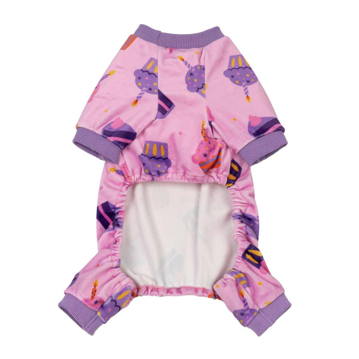Pink dog pjs with a purple and yellow party cake pattern, featuring purple ribbed cuffs and collar, and a white fleece lining