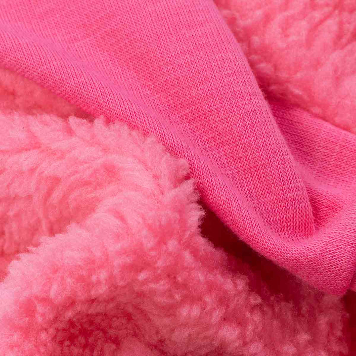 Close-up of pink sherpa and knit fabric layers used in warm dog sweater.