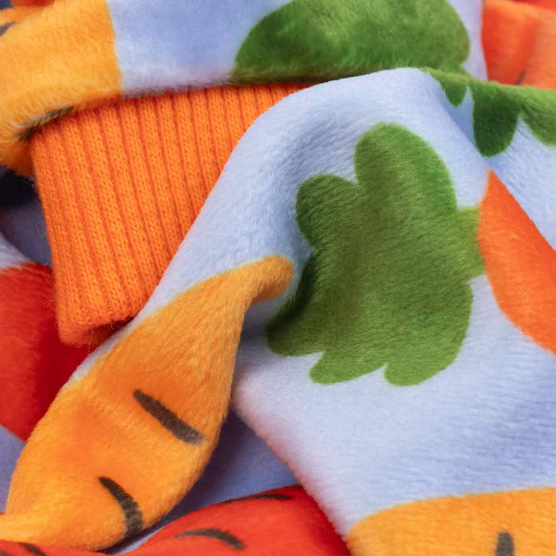 Close up of lightweight velvet carrot print dog pajamas fabric with orange rib trim