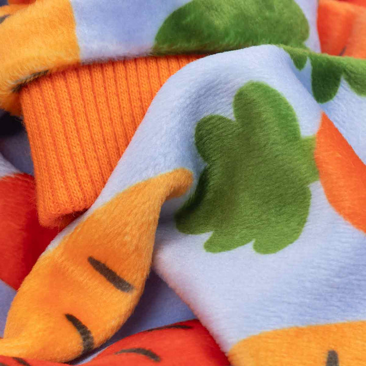 Close up of lightweight velvet carrot print dog pajamas fabric with orange rib trim
