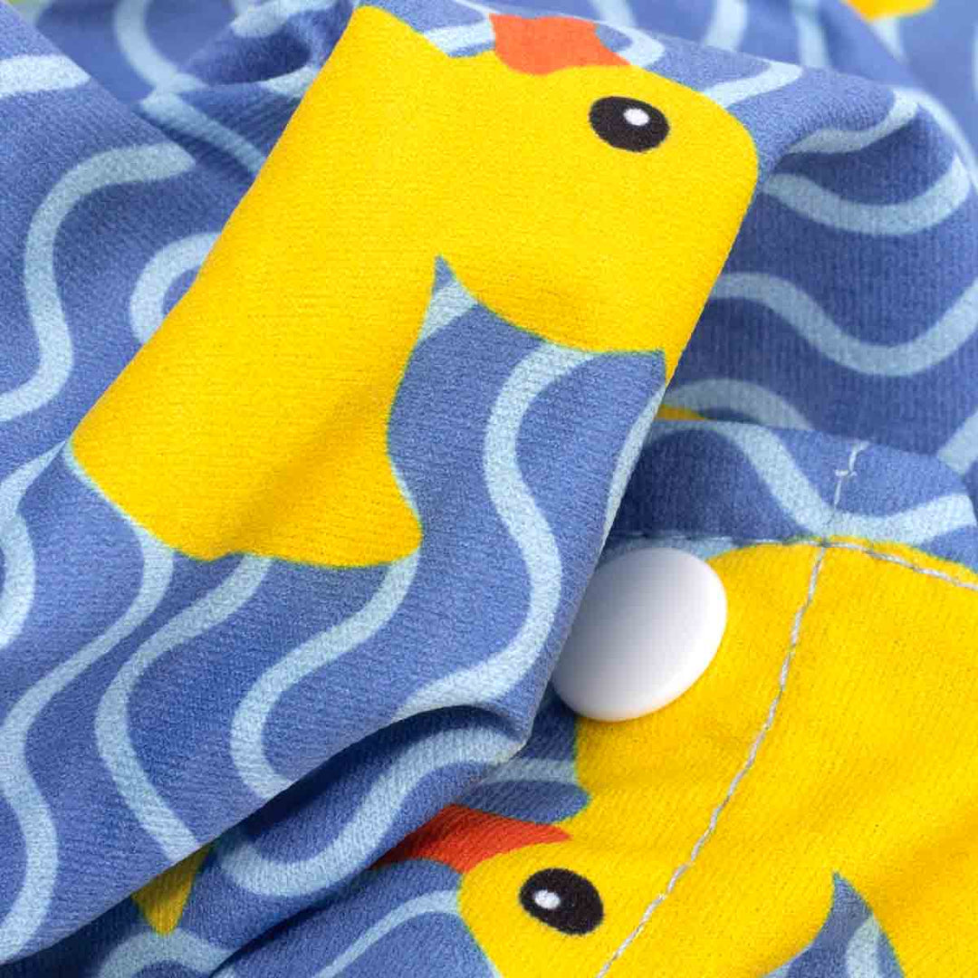 Blue fabric dog shirt with yellow duck and wave print, button closure detail.