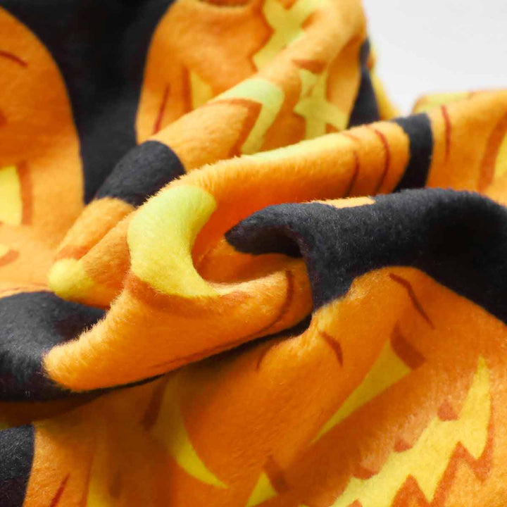 Close-up of pumpkin print velvet fabric for Halloween dog pajamas, orange and black colors.