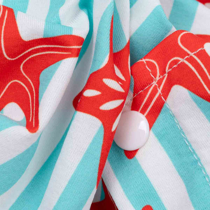 Close-up of a fabric with red starfish and blue stripes, featuring a white button