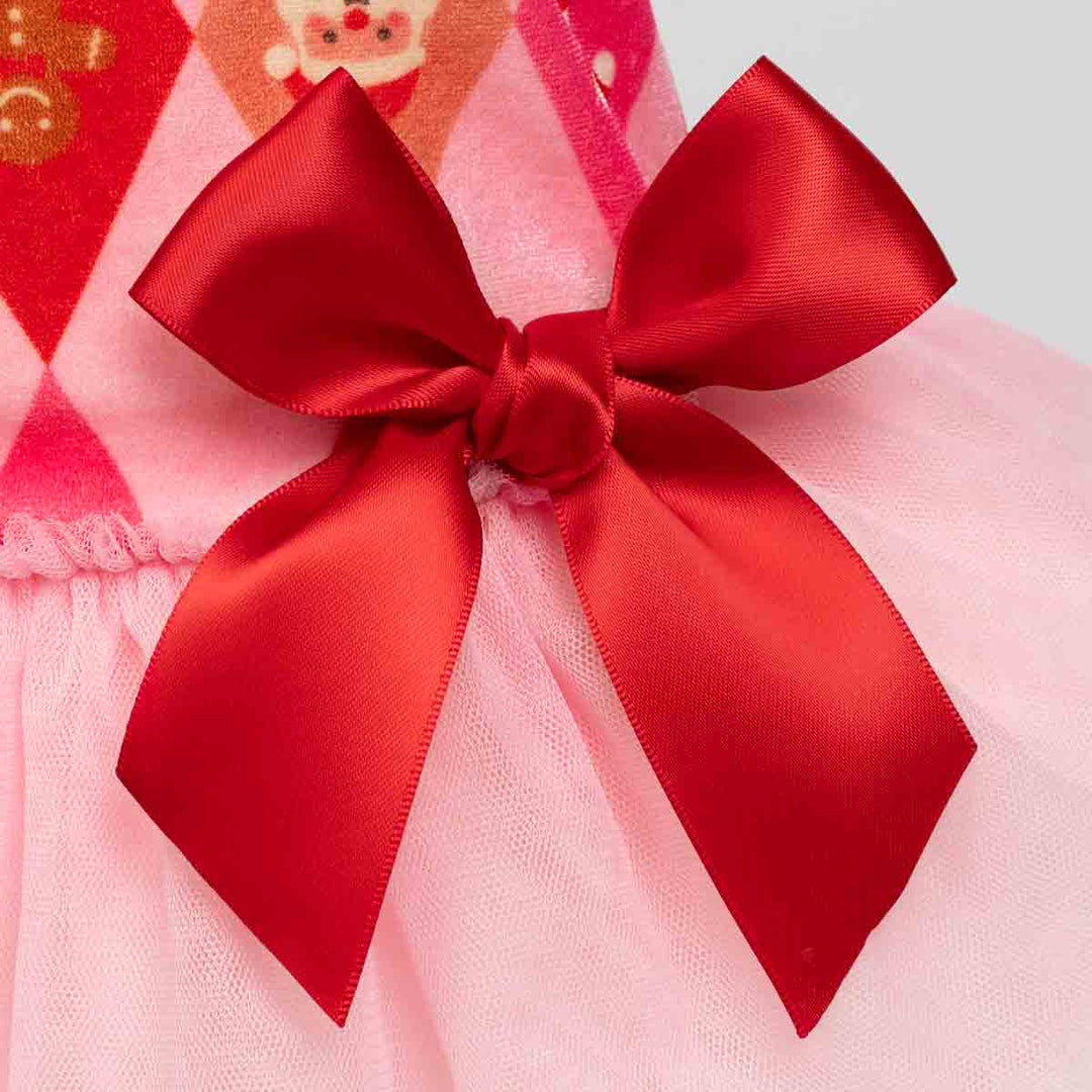 Close-up of a pink tulle dress f or dogs or skirt with a large red satin bow on the front, showing part of a patterned fabric at the top