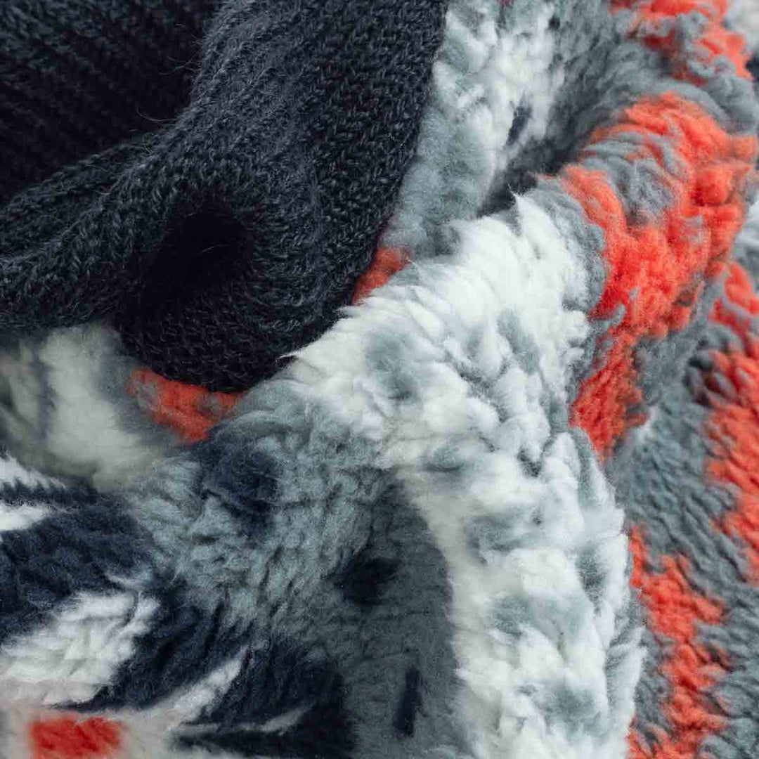 Close-up of dog hoodie fabric with tribal patterns in red, gray, and orange hues.