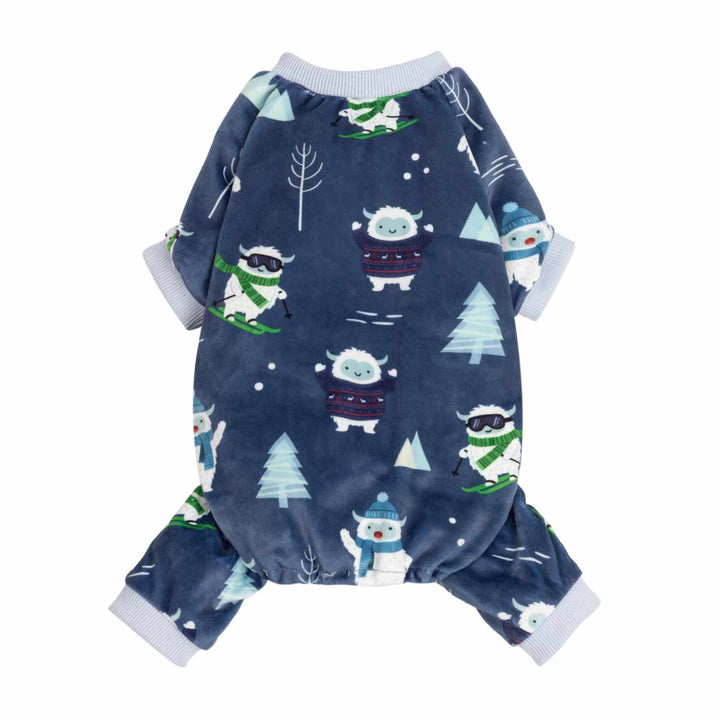 Navy blue pajamas for dogs with a winter print featuring cute cartoon snowman yetis, pine trees, and skiers, finished with light gray ribbed cuffs and collar