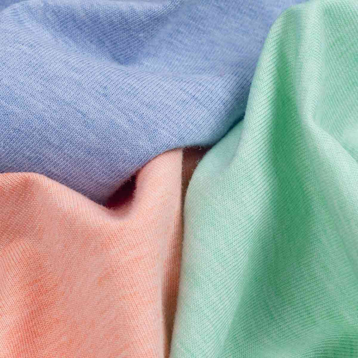Close-up image showing the soft cotton blend fabric of the blue, peach, and green dog shirts.