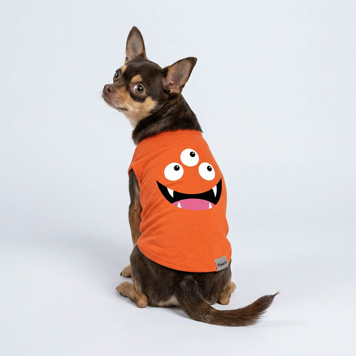 Chihuahua sitting in an orange dog tshirt with a cute monster design, look from back view