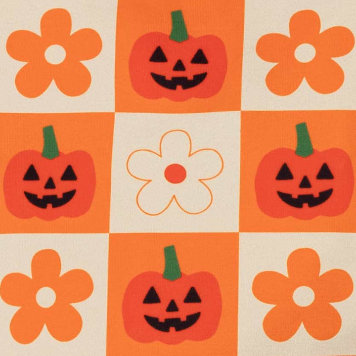 Fabric pattern featuring orange and cream squares, with four orange flower motifs and four orange jack-o'-lantern faces, including one cream flower in the center