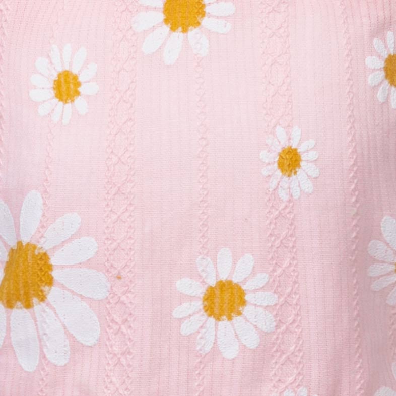 Close-up of a pink fabric with white daisy flowers and yellow centers