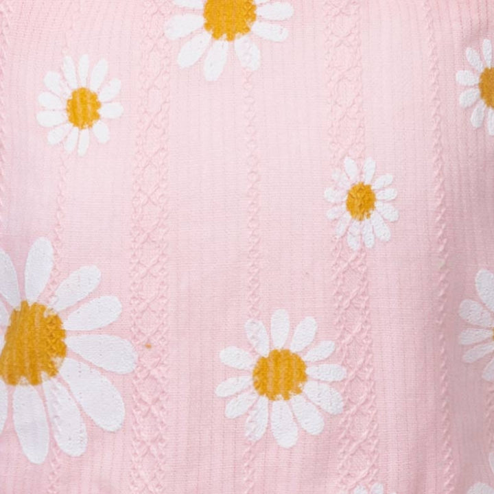 Close-up of a pink fabric with white daisy flowers and yellow centers