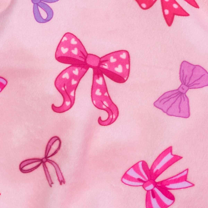 Pattern close up of dog pajamas showing pink and purple bow illustrations on soft fabric.