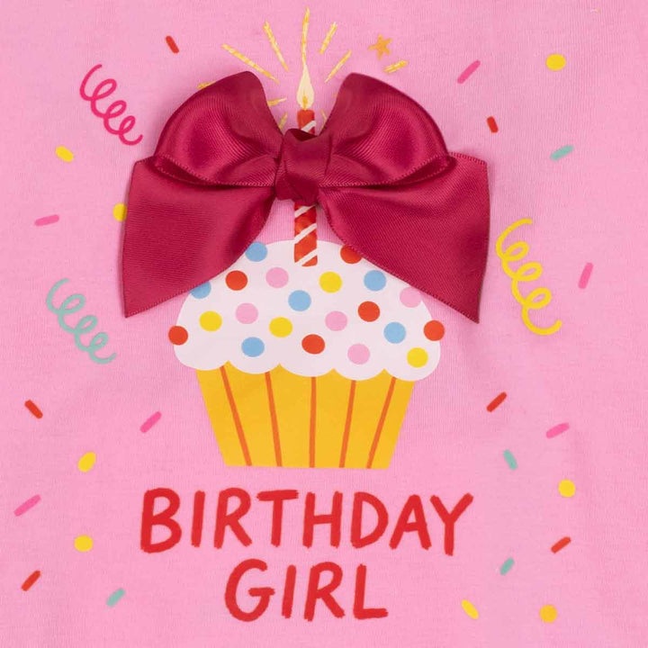 Close up of cupcake, candle, confetti, bow and 'birthday girl' lettering on dog birthday t-shirt