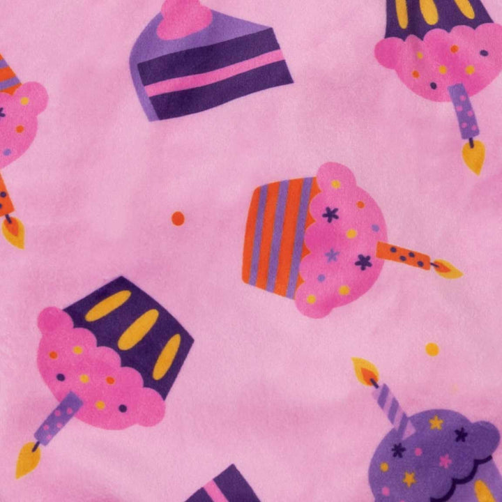 Close-up of a pink fabric with a repeating pattern of colorful cupcakes and birthday candles