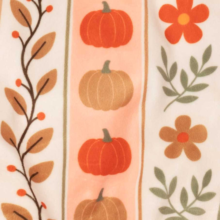 Cose-up of a fabric pattern featuring vertical stripes with autumn motifs, including orange pumpkins, brown leaves, green foliage, and orange flowers on a cream background