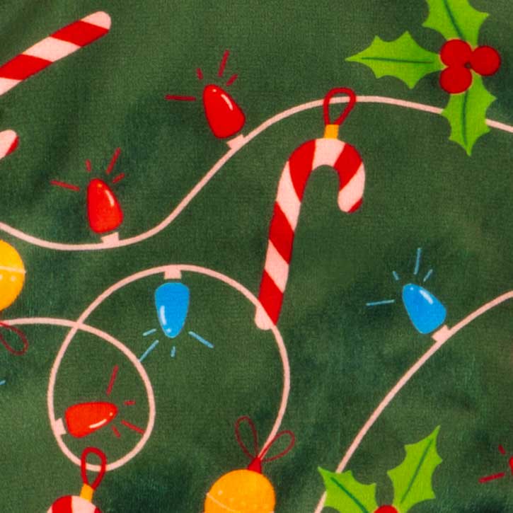 Pattern detail of Christmas dog pajamas featuring candy canes, string lights, and holly leaves.
