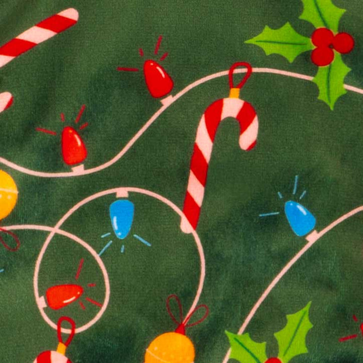 Pattern detail of Christmas dog pajamas featuring candy canes, string lights, and holly leaves.
