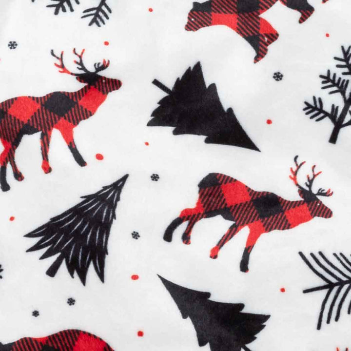 White dog pajamas pattern: red plaid reindeer, bears, trees, snowflakes. Christmas print detail.