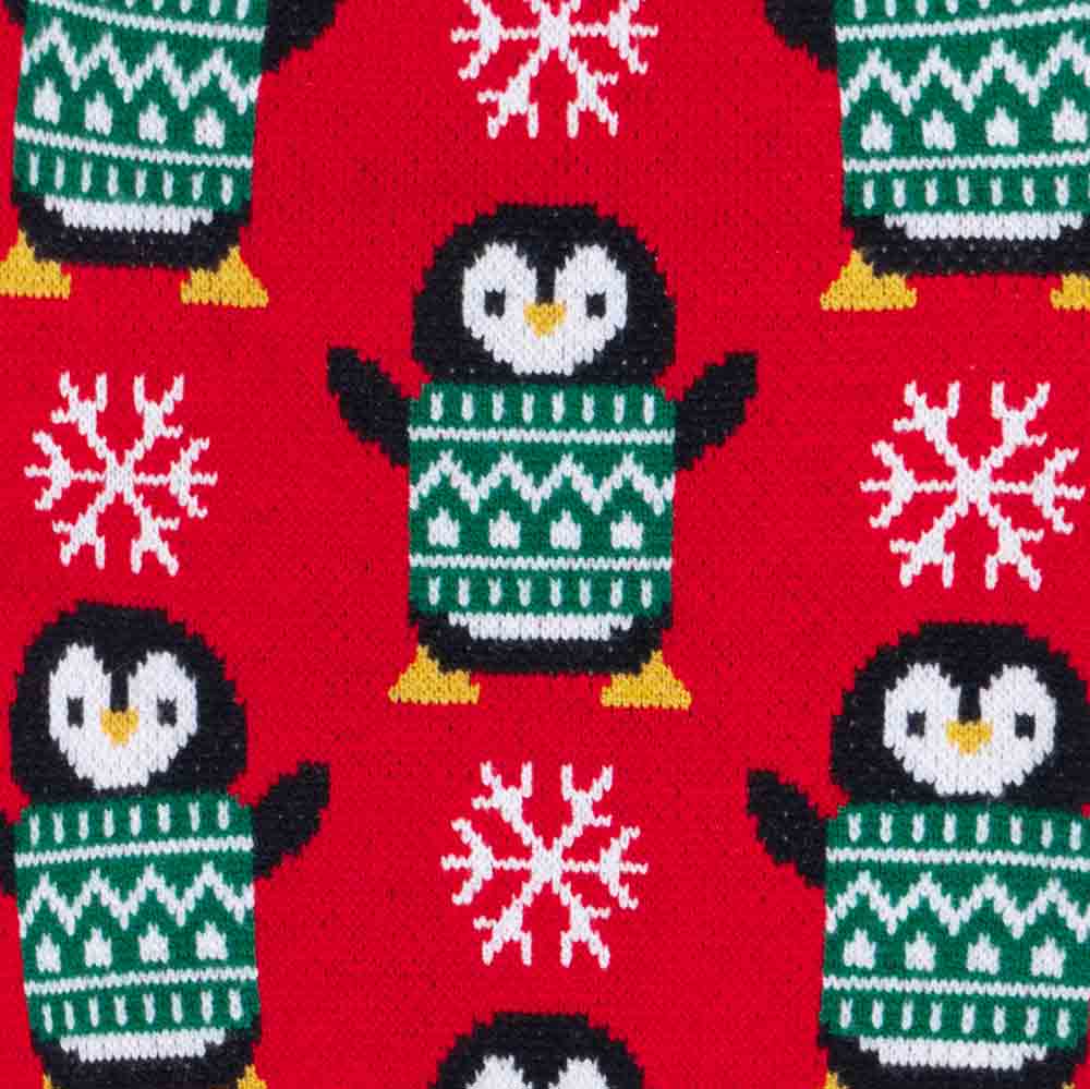 Pattern of penguins in green sweaters and snowflakes on a red background
