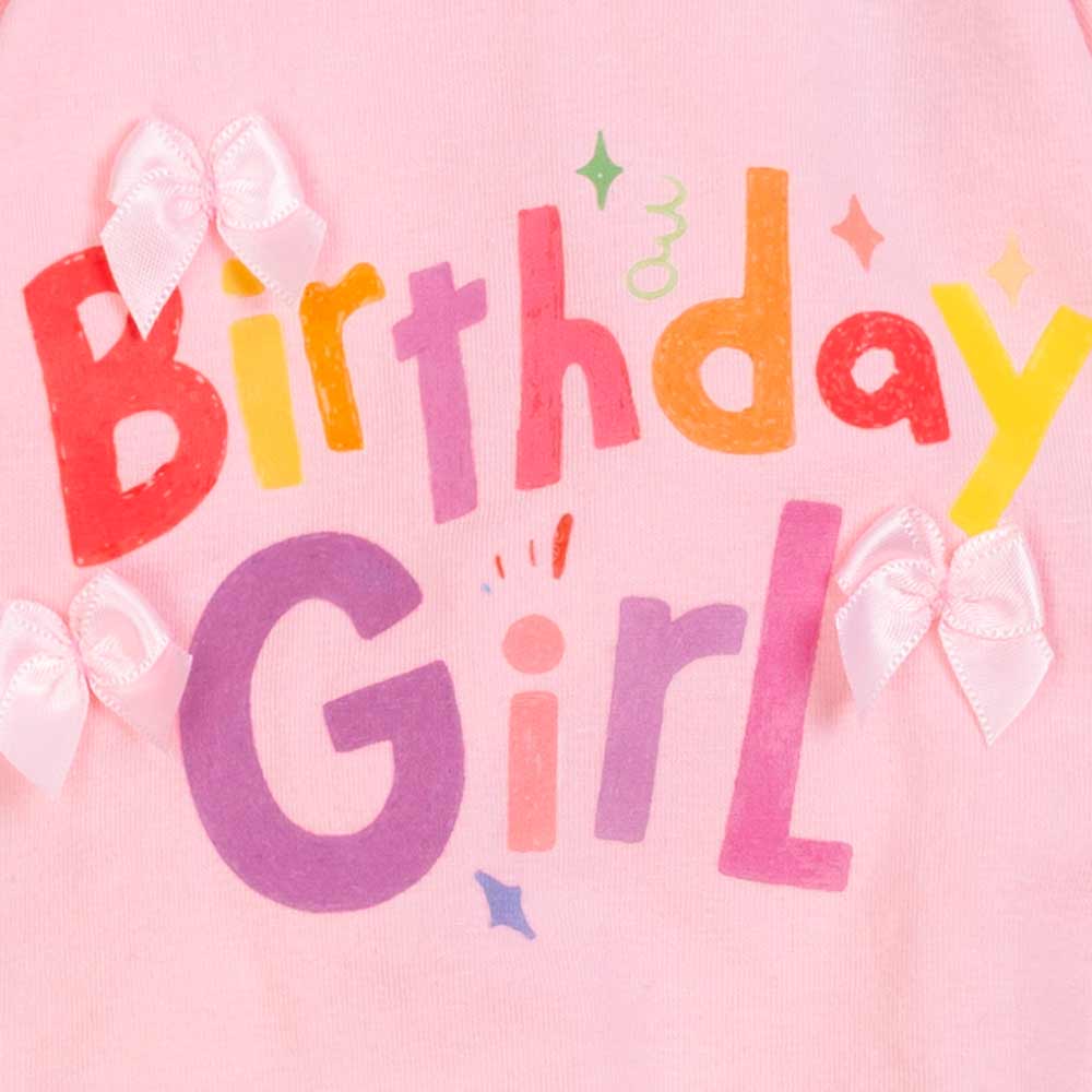 Detail of birthday girl print and bow accents on pink dog pajamas for small dogs.