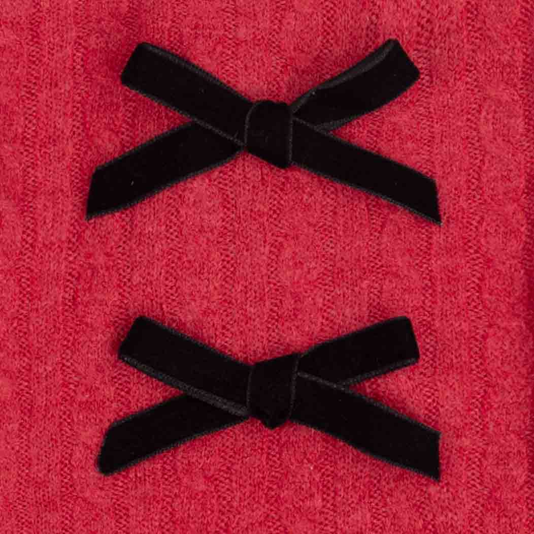 Two black velvet bow accents on a textured red fabric background