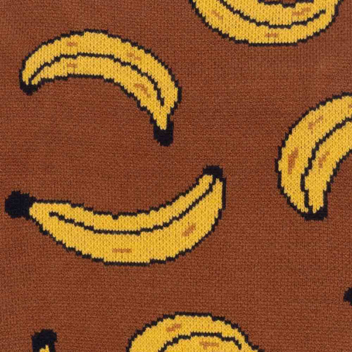 Close-up of a brown dog sweater featuring playful yellow banana knit patterns.