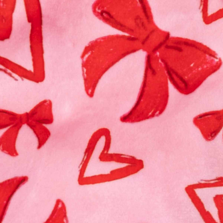 Red bow and heart pattern close-up on pink dog pajamas fabric