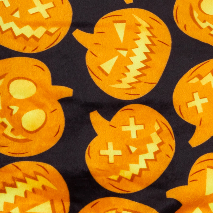 Halloween pumpkin print fabric for dog and cat pajamas. Orange pumpkin faces on black velvet background.