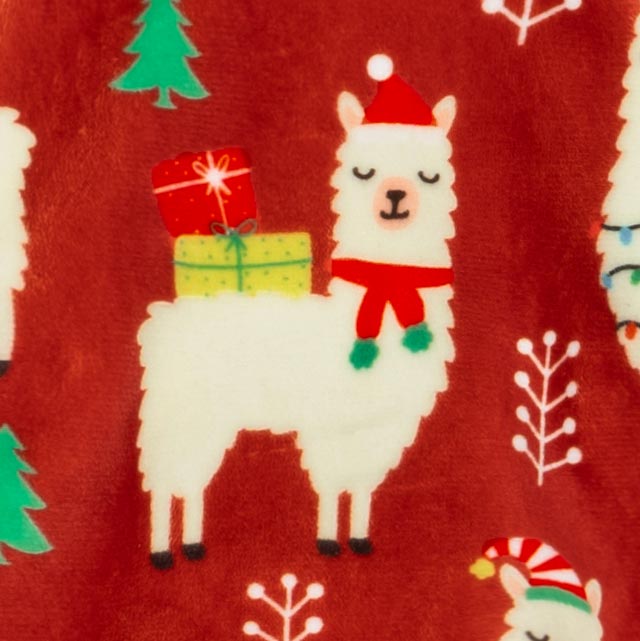 Dog in cozy red alpaca-print pajamas, posing on white blanket with festive winter vibes.