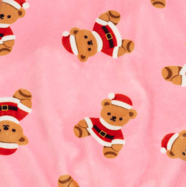 Close-up of a pink plush fabric printed with teddy bears wearing Santa hats and outfits, shown in a repeating pattern