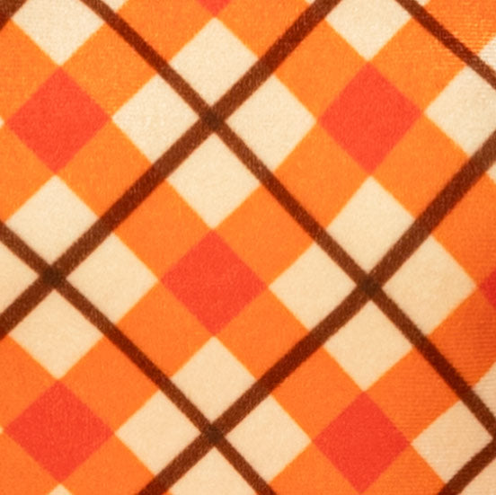 Close-up of a plaid fabric pattern featuring orange, cream, and red diamonds outlined by dark brown intersecting lines