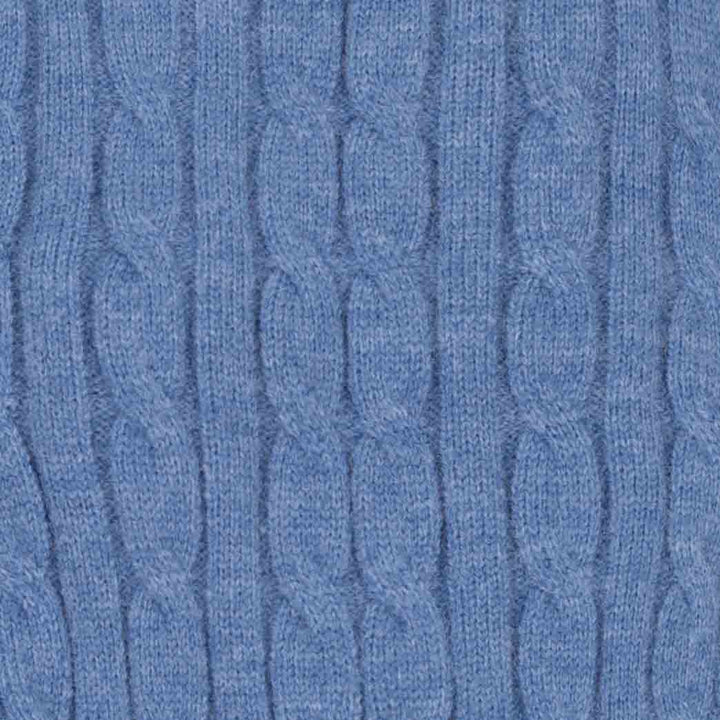 Close-up of a blue cable-knit fabric texture, showing the detailed knit pattern and heathered blue color