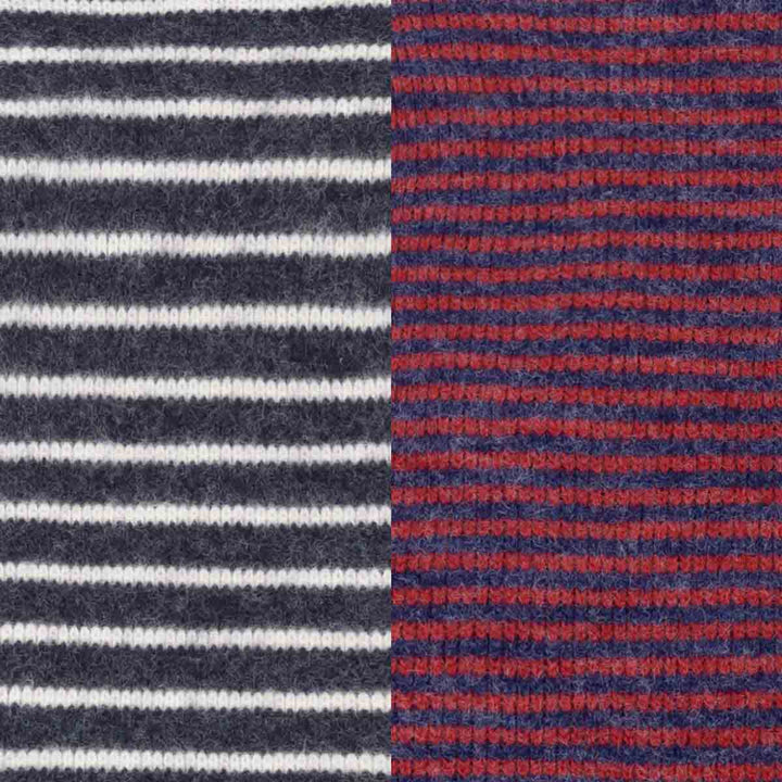 Close-up of a knitted fabric with two vertical color-blocked sections: the left side has dark navy and white horizontal stripes, and the right side has navy and red horizontal stripes