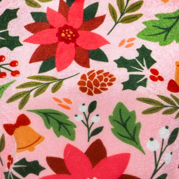 Detailed view of poinsettia and holly prints on pink velvet dog dress fabric.