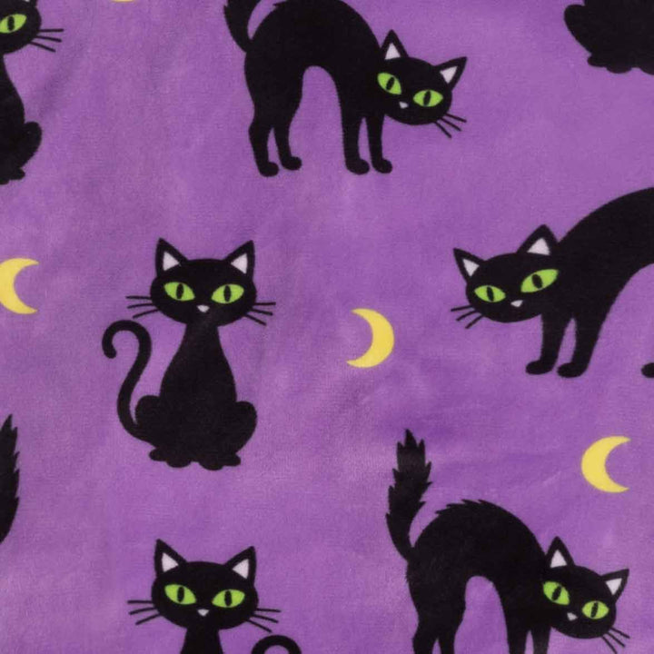 Purple fabric with a repeating pattern of black cats with bright green eyes and small yellow crescent moons