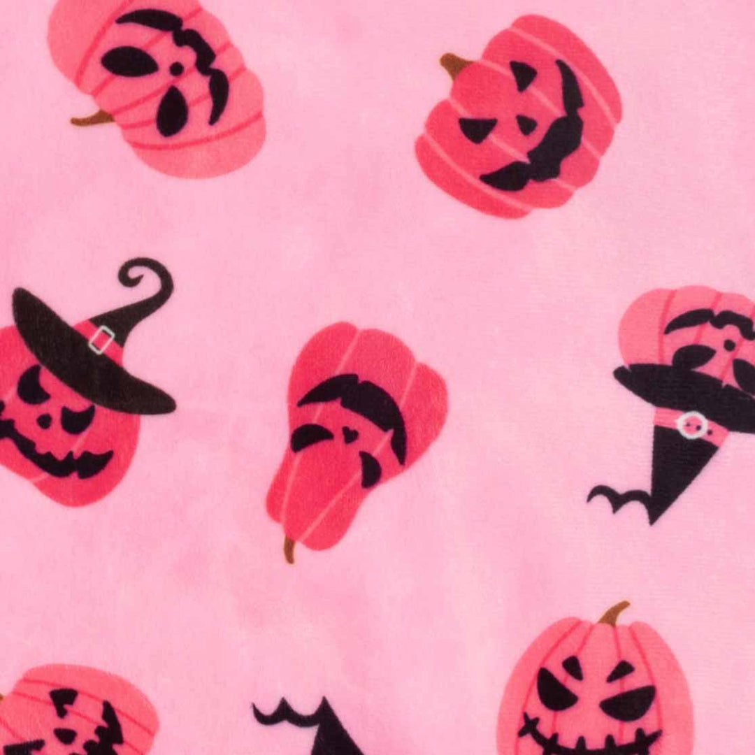 Pink dog pajama fabric detail: soft polyester with playful Halloween pumpkin and witch hat patterns.