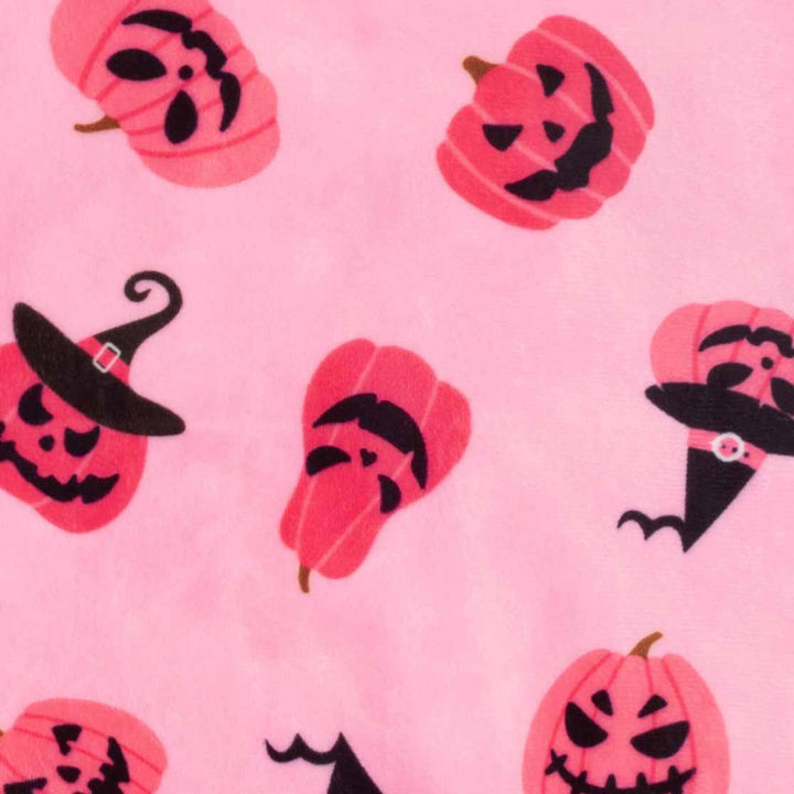 Pink dog pajama fabric detail: soft polyester with playful Halloween pumpkin and witch hat patterns.