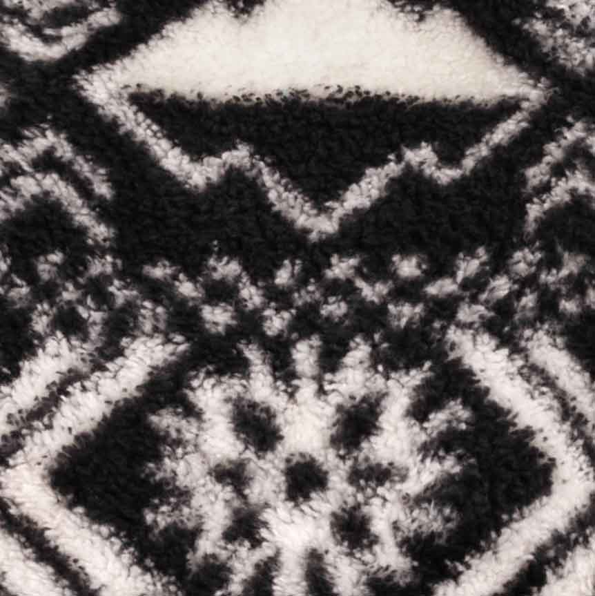 Close-up pattern detail of black and white fleece dog pajamas with geometric winter-inspired design.