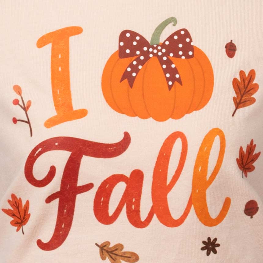 Close-up of a cream-colored fabric featuring a printed autumn graphic that reads 'I Love Fall' with an orange pumpkin, brown polka-dot bow, and scattered fall leaves