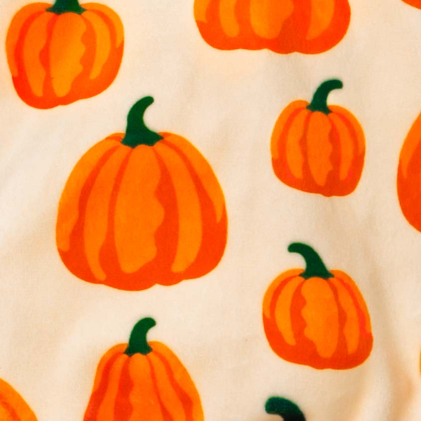 Pumpkin patterned fabric detail on festive dog pajamas for Halloween season.